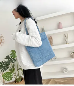 Dettaglio della borsa tote in denim azzurro con tasche frontali e cuciture a contrasto