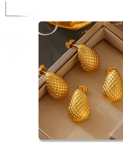 Macro detail of gold teardrop earrings with mesh texture in a velvet jewelry box