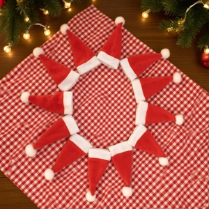 Detailed view of mini red Christmas hats arranged on a festive checkered fabric background