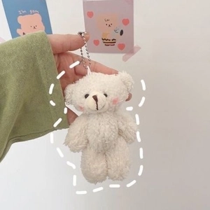 Close-up of cute white plush bear pendant with silver chain detail on school backpack