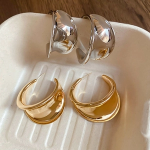Macro shot of stylish gold and silver C-shaped metal stud earrings in a tray