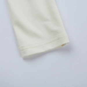 Gros plan détaillé des poignets de robe en maille blanc cassé et coutures renforcées