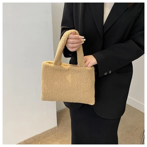 Detailed view of beige plush handbag texture being held by a model on white background