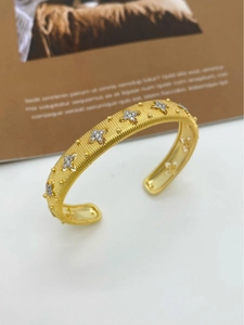 Macro shot of gold brushed metal cuff with star-shaped zircons and intricate details
