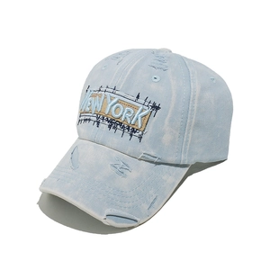 Close-up of New York 3D embroidery on light blue washed denim cap with distressed details