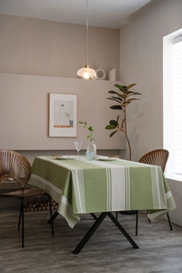 Detailed texture of green and white striped cotton linen tablecloth on a rectangle dining table