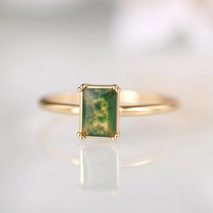 Elegant gold ring featuring a rectangular emerald green stone in a classic four-prong setting