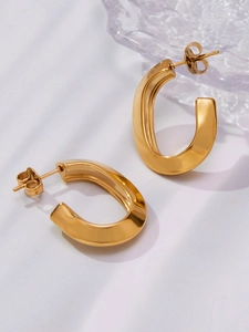 Macro detail of chunky gold-plated U-shaped earrings with a polished mirror finish