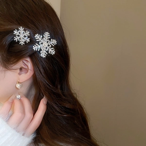Close-up of sparkling silver snowflake hair clips with rhinestones on wavy brown hair