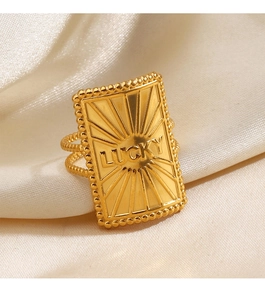 Detailed close-up of golden Lucky ring with sunflower texture on cream silk fabric