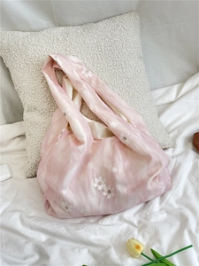 Pink canvas tote bag with white flower embroidery against white pillows and tulips