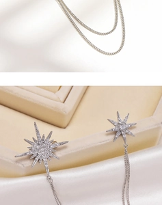 Detail of silver eight-pointed star earrings with crystal inlay and chain tassels