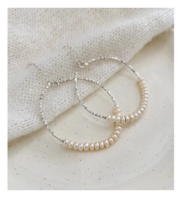 Close-up of small white freshwater pearls and irregular silver beads on a textured surface