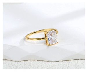 Macro shot of gold square zircon ring with elegant four-prong setting on textured surface