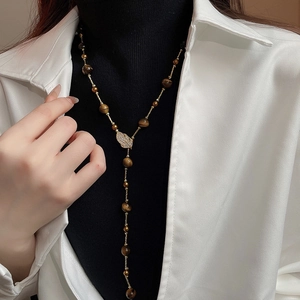 Tiger eye bead Y-necklace with gold leaf pendant and zircon crystals on black sweater