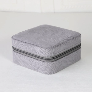 Detailed view of light gray square jewelry storage box with zipper and fabric texture