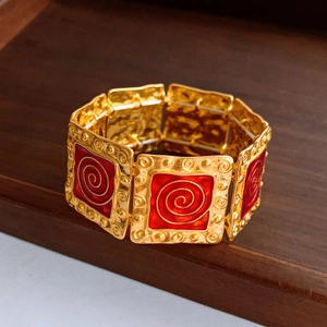 Macro detail of vintage gold bracelet with square red enamel modules and spiral patterns