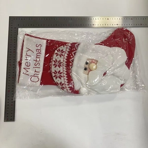 Detail of red knitted Christmas stocking with Santa Claus 3D figure and white embroidery