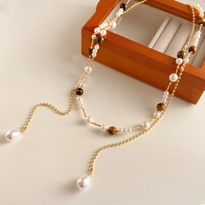 Detail of vintage necklace with white pearls and tiger eye stones on a wooden box