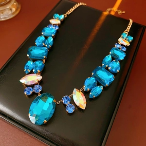 Detailed close-up of blue and iridescent stones set in a gold geometric pendant necklace