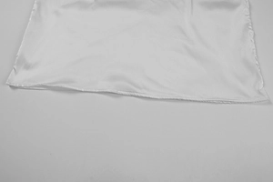Close-up of the smooth white satin hem with high-gloss finish and neat stitching detail
