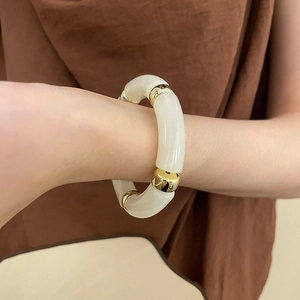 Close-up of cream acrylic tube beads and gold metal spacers on a vintage bracelet