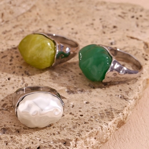 Macro detail of three retro hammered rings with green and pearl acrylic stones