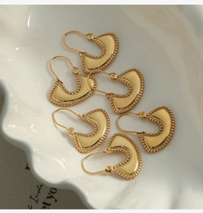 Detailed macro view of gold-plated U-shaped earrings with fine milgrain edges
