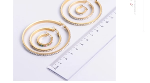 Detailed size comparison of gold hoop earrings set with rhinestones against a ruler