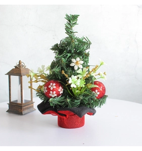 Close-up of a mini Christmas tree with red baubles and white flowers on a festive table