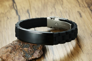 Detail of black silicone bracelet on stone with polished stainless steel plate