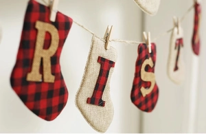 Detail of Christmas burlap sock bunting with red plaid accents and letter embroidery