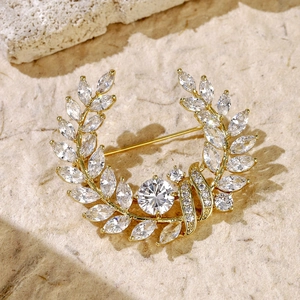 Macro detail of a golden laurel wreath brooch with sparkling marquise and round crystals