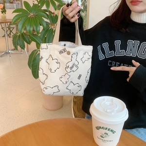 Detail of white corduroy lunch bag featuring bear print and secure metal snap closure