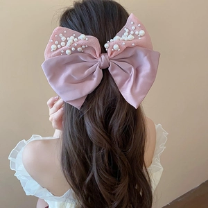 Detailed view of a large pink double-layered bow hair claw clip with pearl accents