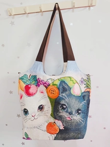 Detail der Canvas-Einkaufstasche mit gestickten Katzenmotiven und einem großen orangefarbenen Knopf