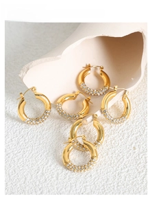 Detail of three pairs of gold-plated hoop earrings with three rows of paved crystals