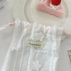 Detailed macro view of white floral embroidery and pink ribbon on a fabric drawstring pouch
