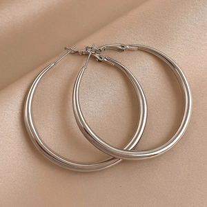 Polished silver geometric hoop earrings on champagne silk fabric, minimalist chic style
