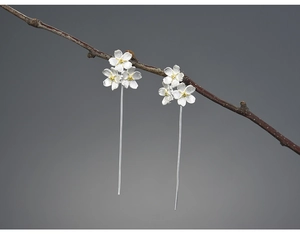 Macro detail of S925 silver forget-me-not flower drop earrings on a dry branch