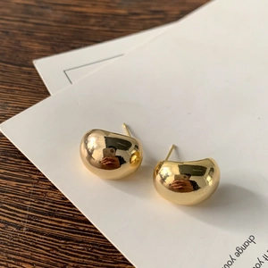 Detalle de pendientes de bola dorados pulidos sobre una superficie de madera oscura