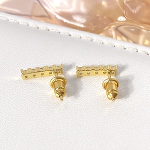 Macro detail of gold bar earrings with clear zircon stones and secure bullet backs