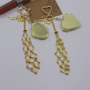 Close-up of golden metal locket keychain featuring intricate mesh tassels and a star hook