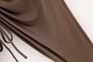 Macro shot of dark brown ruched fabric detail with fine texture and slim drawstring cord
