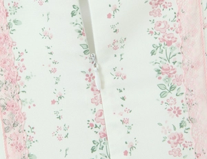 Dettaglio di cerniera invisibile con pizzo rosa e stampa floreale su vestito bianco