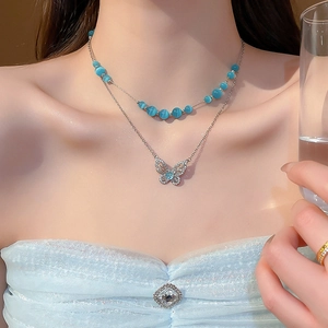 Detail of double-layer necklace featuring a zircon butterfly pendant and blue cat eye stones