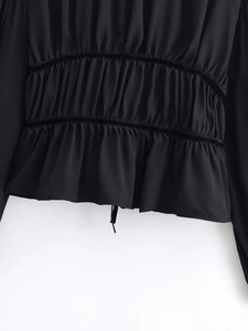 Detail shot of black ruffled fabric with parallel velvet elastic bands and precise pleats