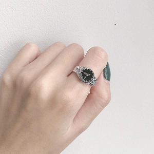 Close-up of creative silver watch-shaped ring with black dial on finger