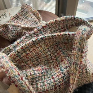 Macro detail of multi-colored knit texture and silver magnetic buckle on shoulder bag