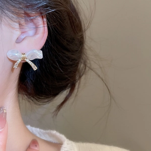 Detail of bow earrings with pearls and zircon stones worn on model for elegant style
